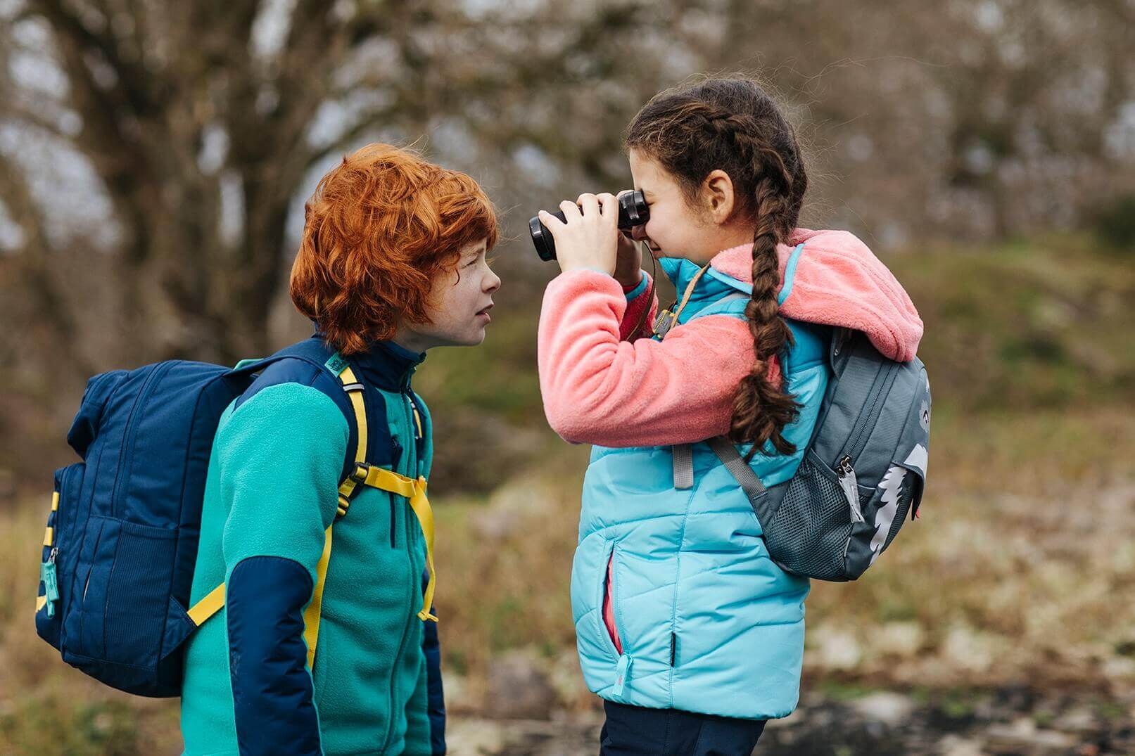 Zwei Kinder spielen mit einem Fernglas.