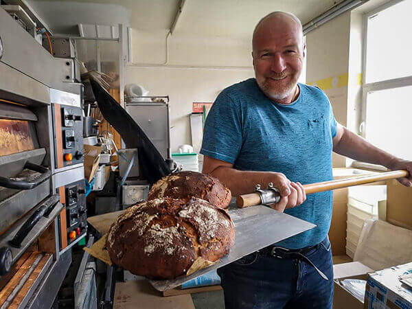 Bergfreund holt Brot aus dem Ofen.