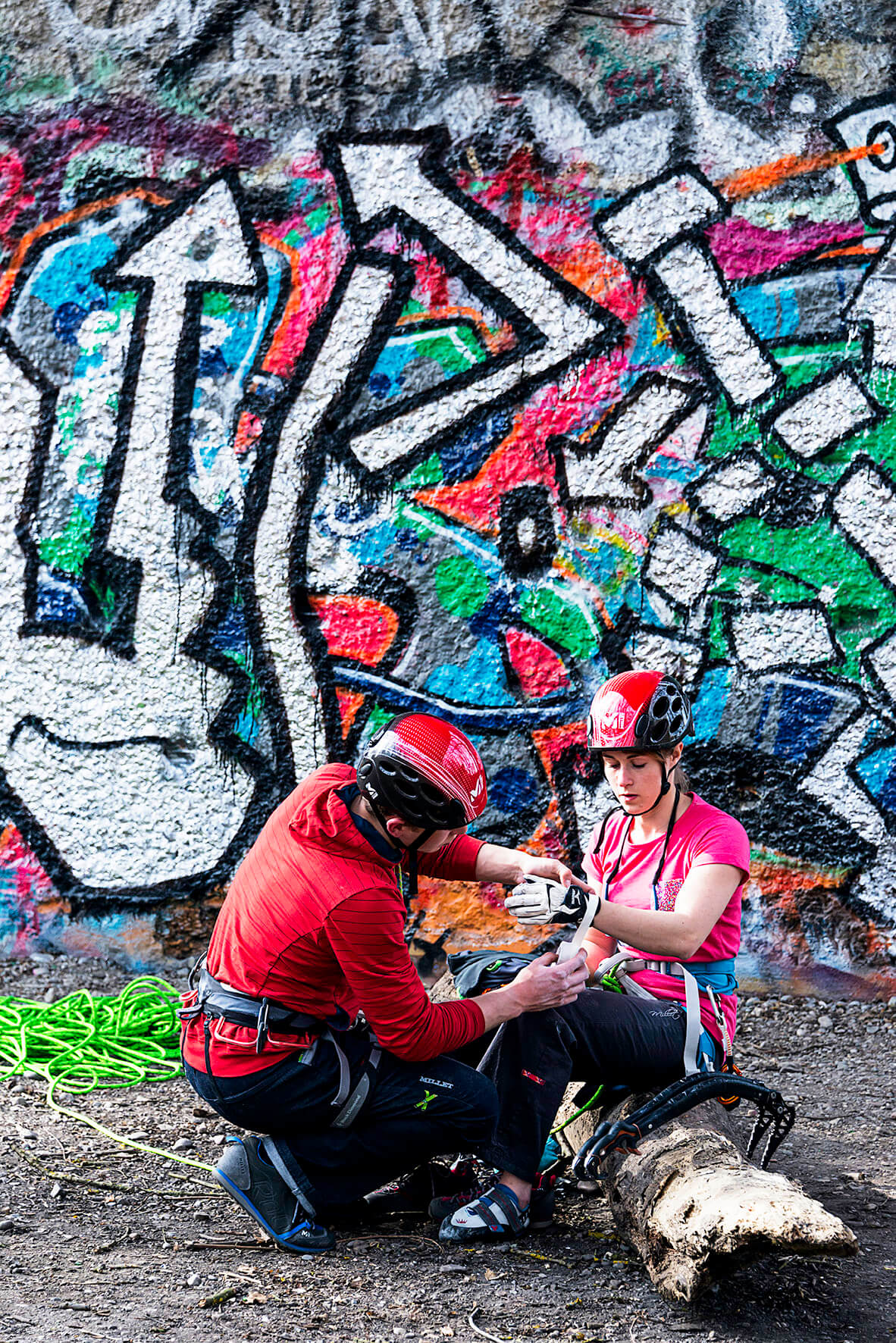 Mann unterstützt Kletterin beim Vorbereiten der Ausrüstung vor dem urban climbing