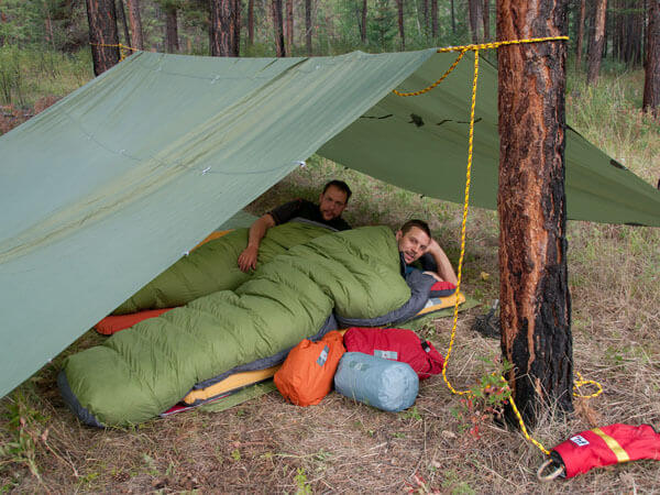 Zwei Outdoor-Wanderer im Schlafsack unter ihrem Tarp