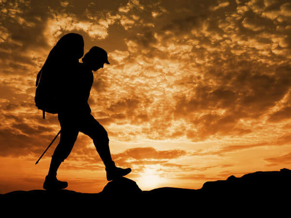 Bergfreund wandert bei Sonnenuntergang mit Wanderrucksack.