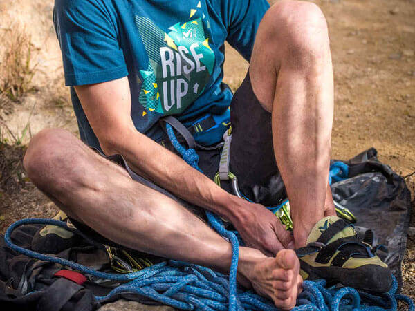Ein Mann zieht seine Kletterschuhe aus