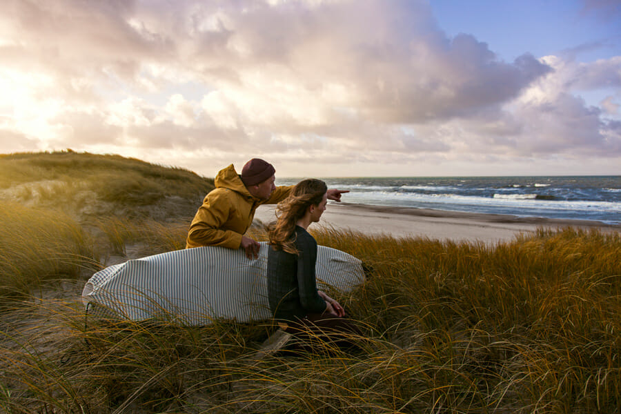 Mann und Frau mit Surfboard am Strand