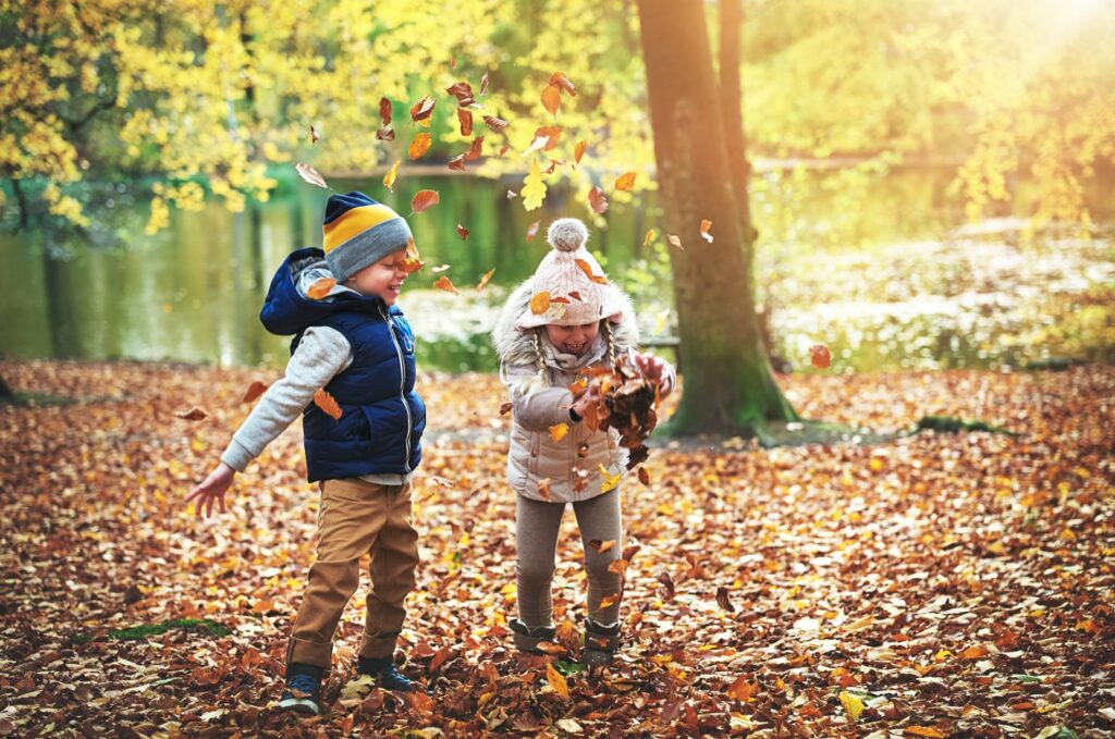 Zwei Kinder spielen mit Laub