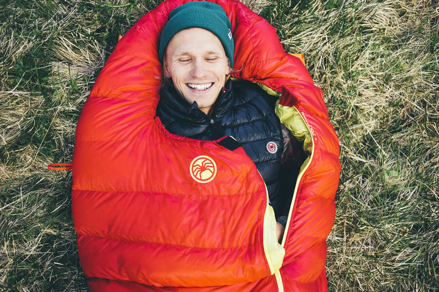 Mann liegt in einem roten Schlafsack.