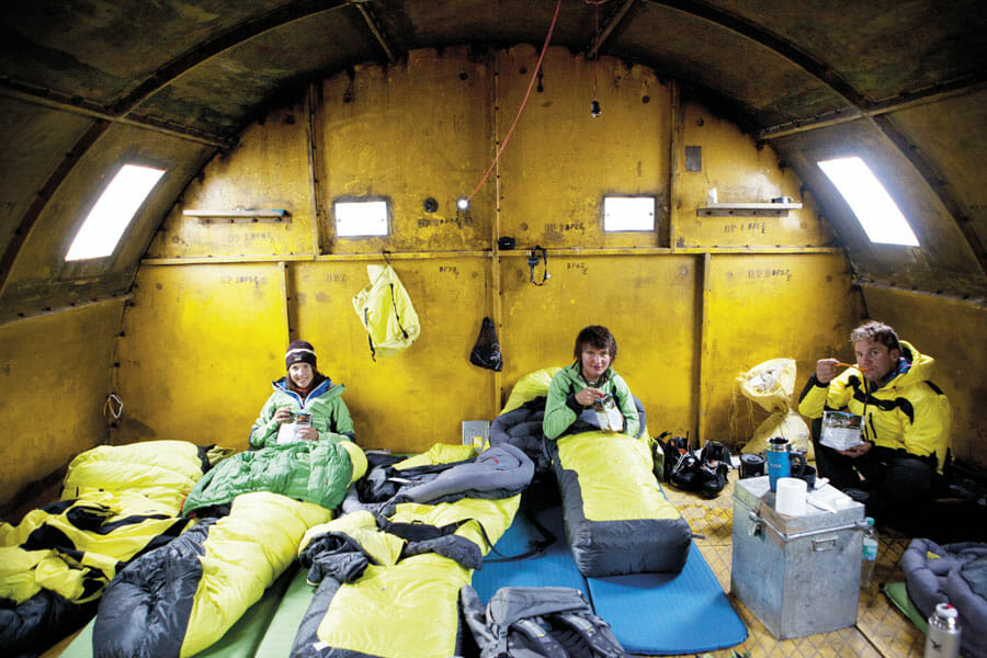 Drei Personen übernachten in Silo mit Schlafsäcken und Isomatten.