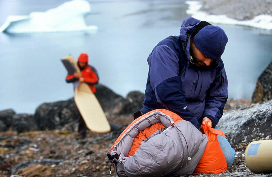 Mann packt einen Schlafsack in einen Packsack.