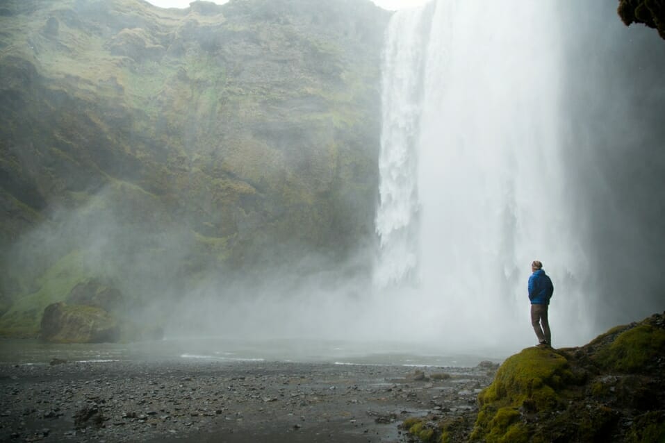 Person steht mit ThermoBall Jacke an einem Wasserfall