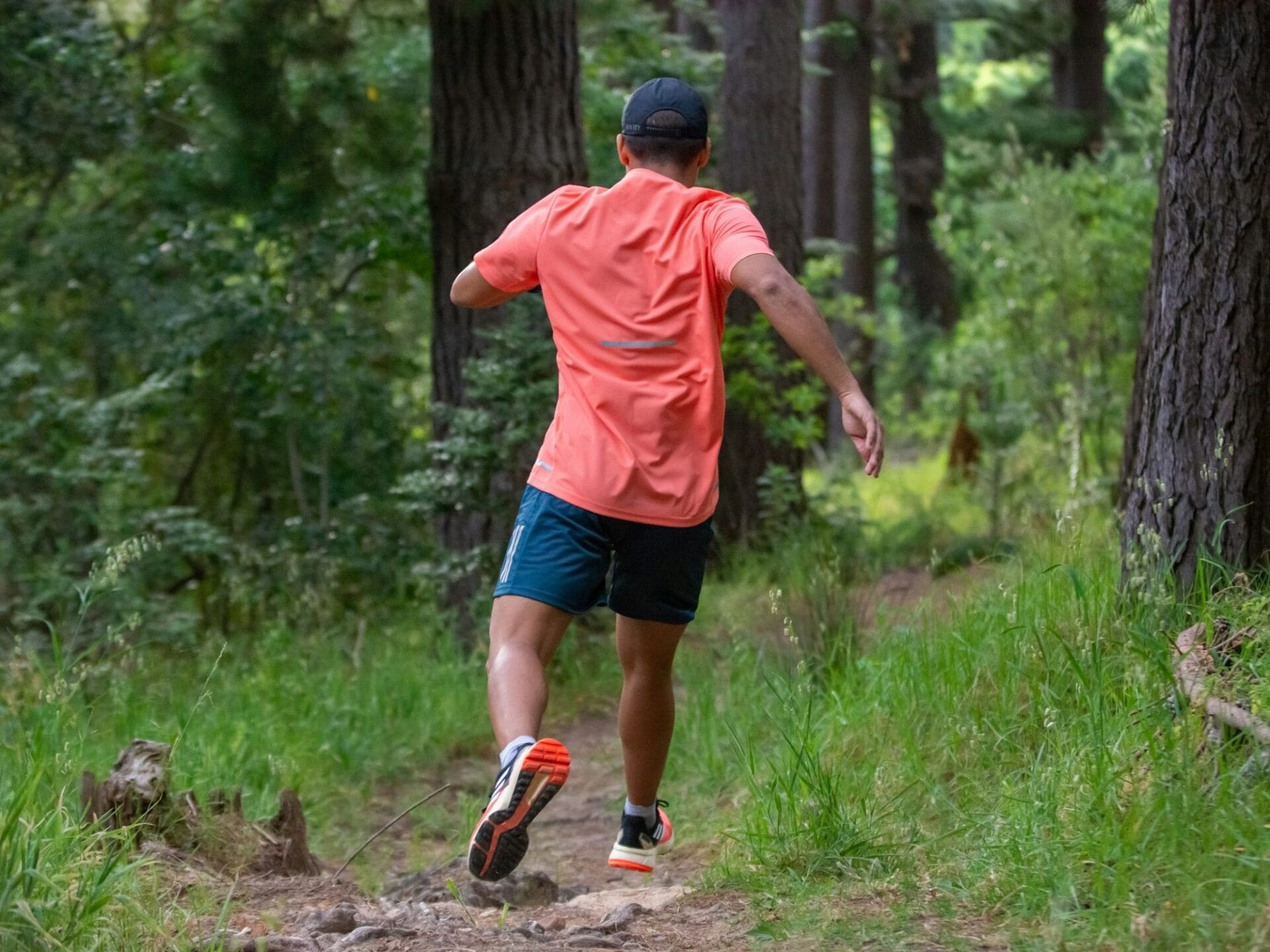 Mann beim Downhillrun im Wald von hinten