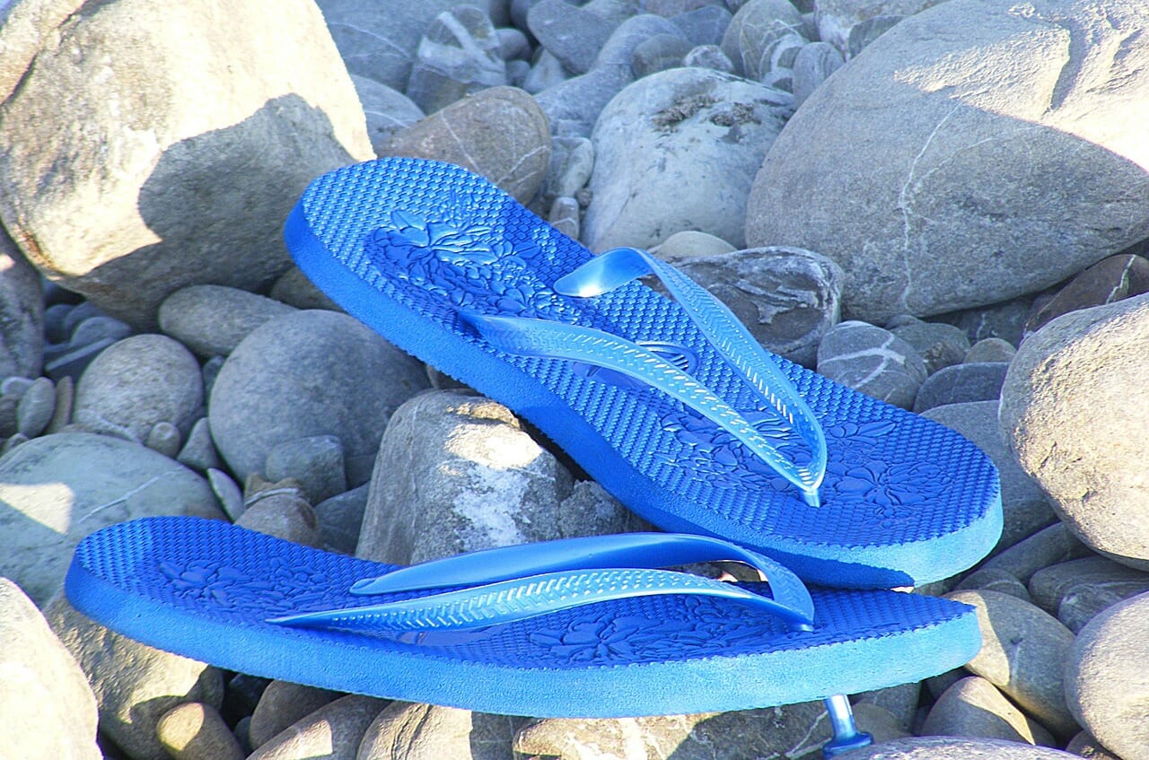 Blaue Flip-Flops auf steinigem Untergrund
