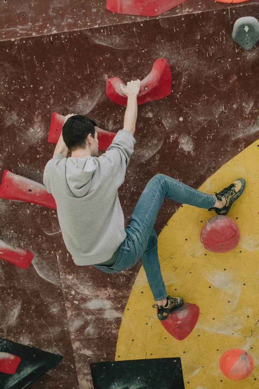 Mann an der Boulderwand macht einen Heelhook