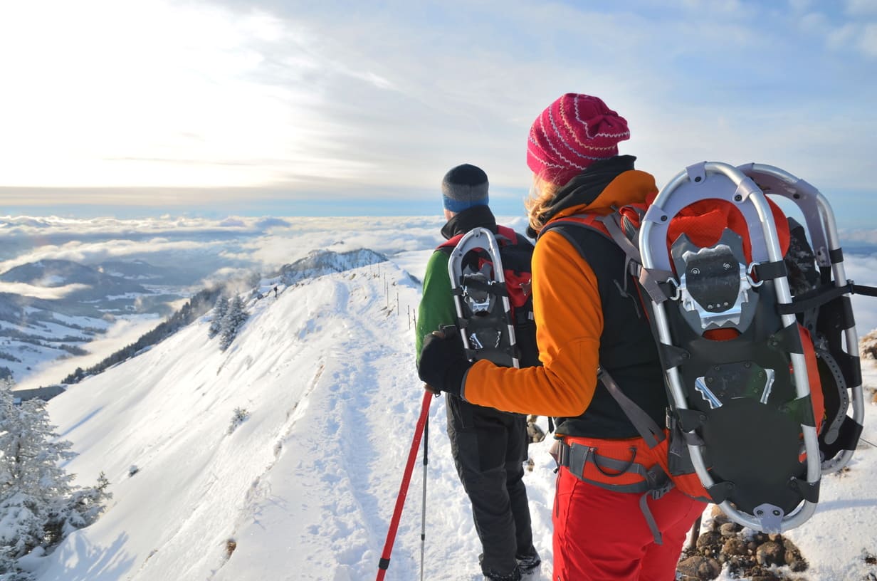 Zwei Leute stehen an einem verschneiten hang und blicken in die weiße Landschaft