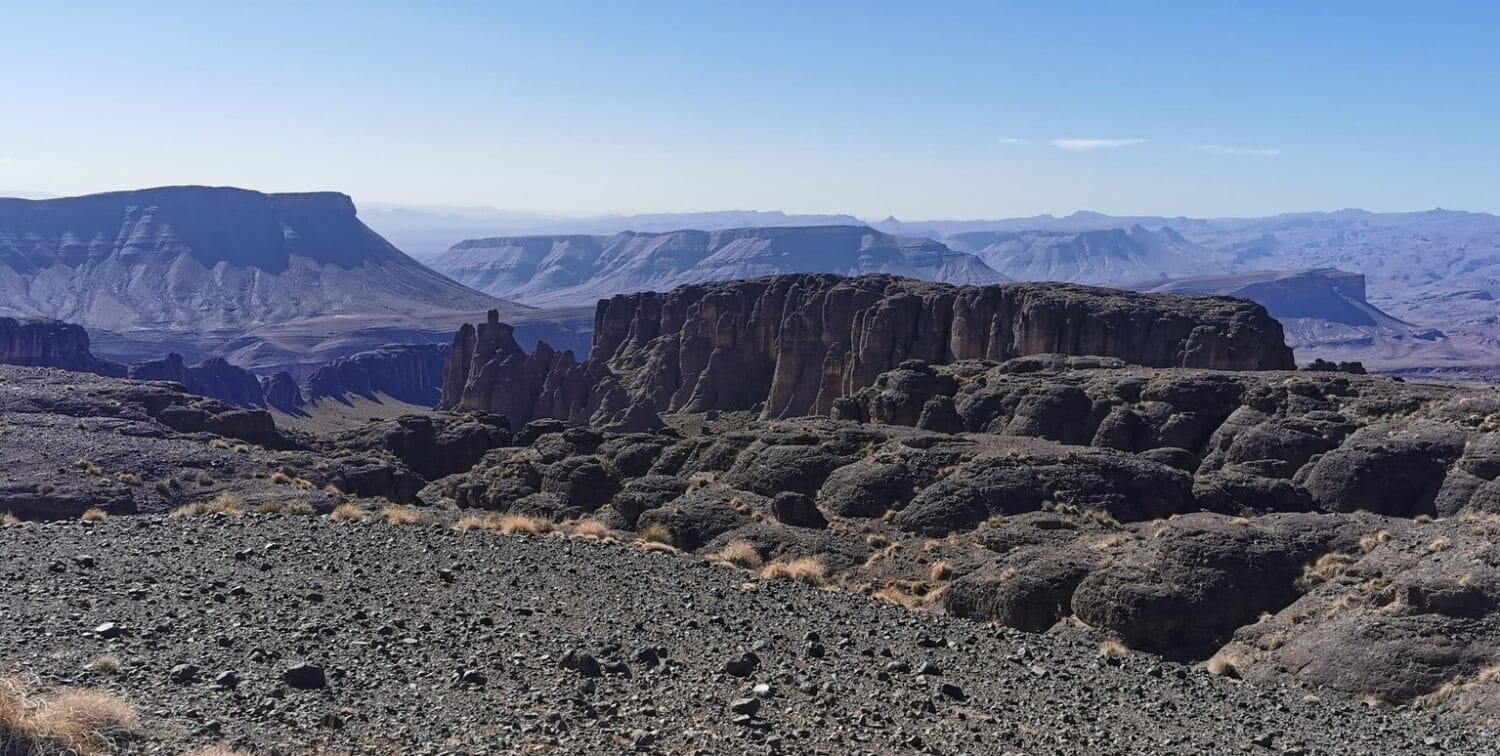 Felsige Landschaft in der Wüste von Marokko mit dunklen Gesteinen und weitem Ausblick.