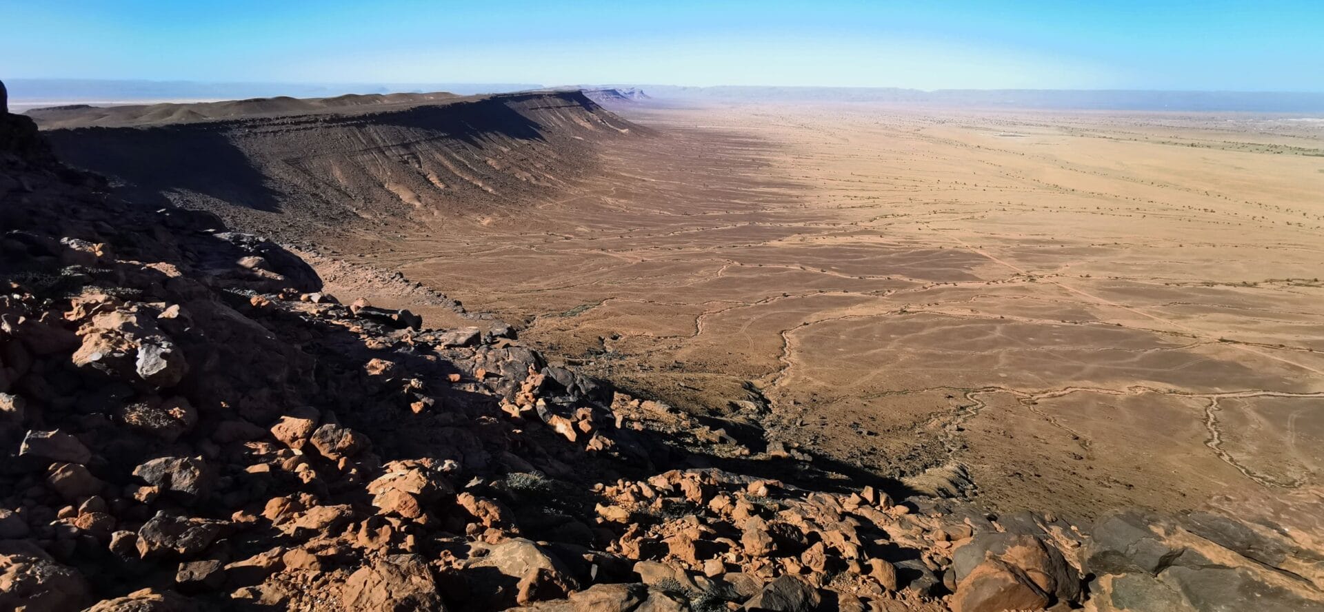 Bild von Sahara mit einer Bergformation links und weit im Hintergrund