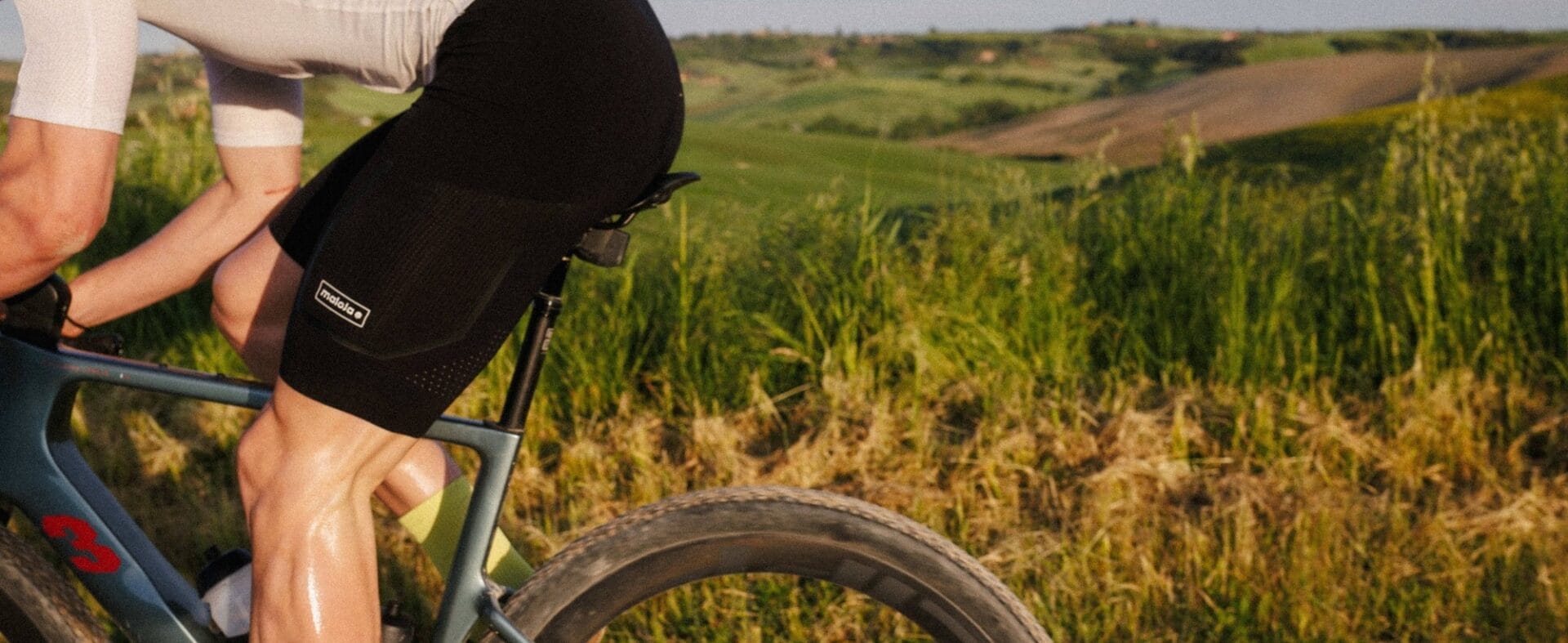 Rennradler auf seinem Rad und im Hintergrund grüne Wiese