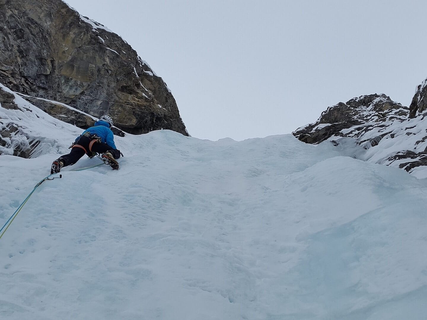 Person erklimmt Eiswand mit Eispickel