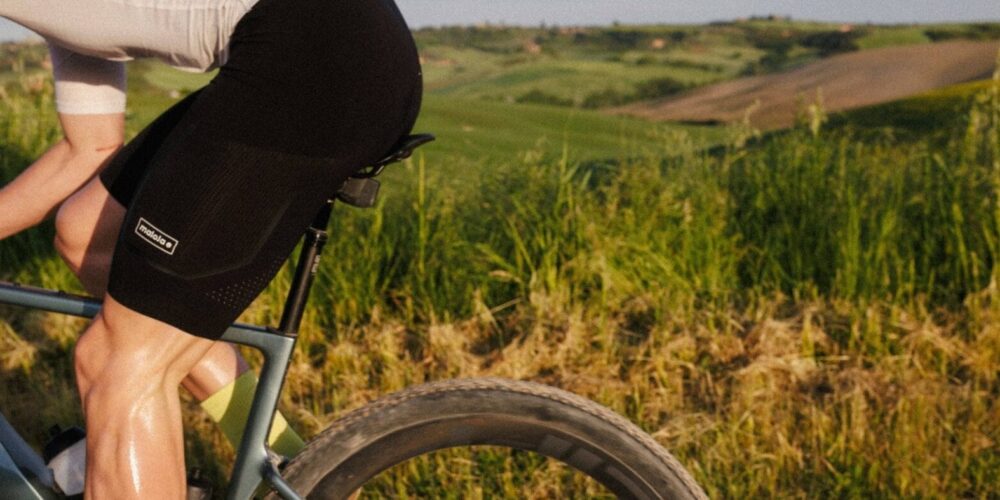 Rennradler auf seinem Rad und im Hintergrund grüne Wiese