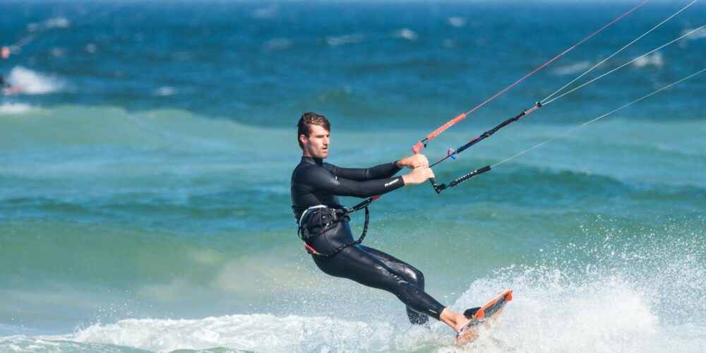 Mann mit Neoprenanzug beim Kitesurfen