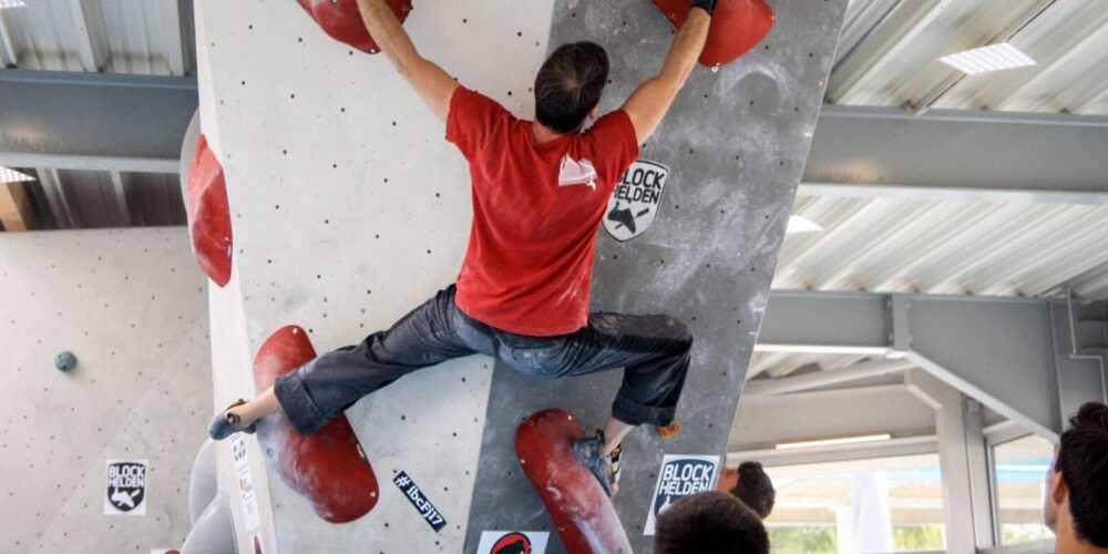 Gespreizter Mann an der Boulderwand