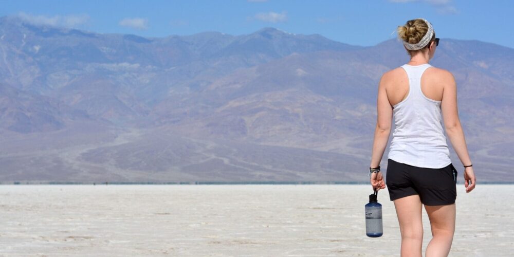 Frau mit Flasche in der Hand in der Wüste