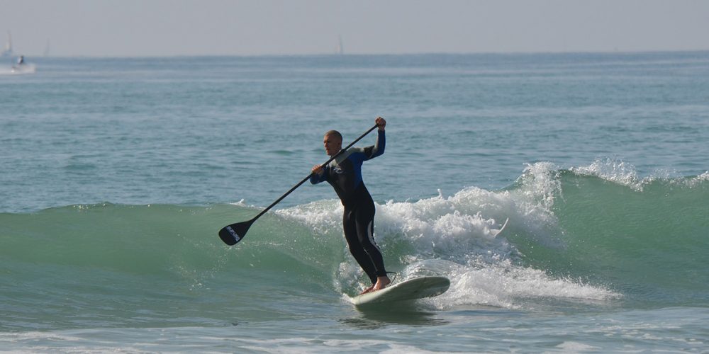 Stand-Up Paddle Surfer reitet eine Welle.