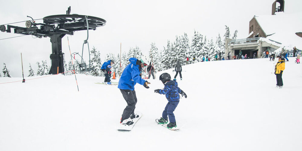 Snowboardlehrer mit Snowboard-Anfänger